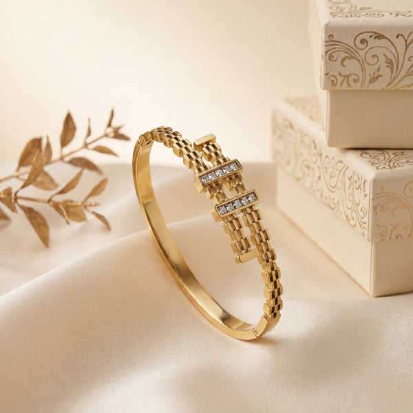 Gold bracelet with diamond accents on a beige surface with decorative elements